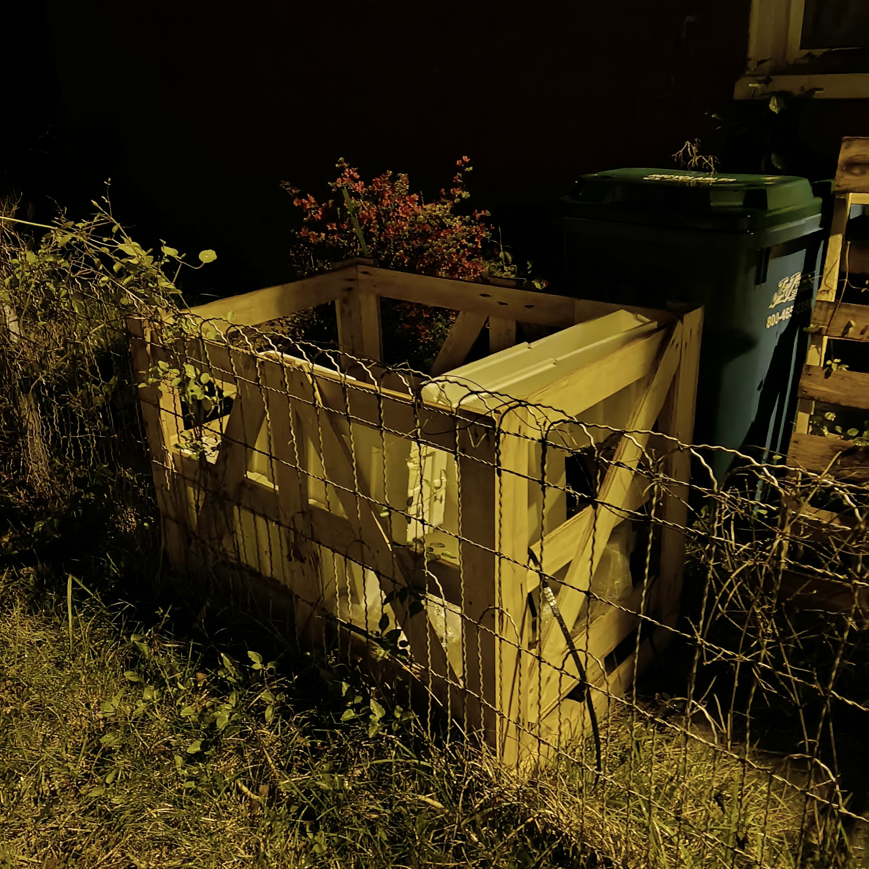 holders, blue for garbage, wiry little fence, grasses and bushes