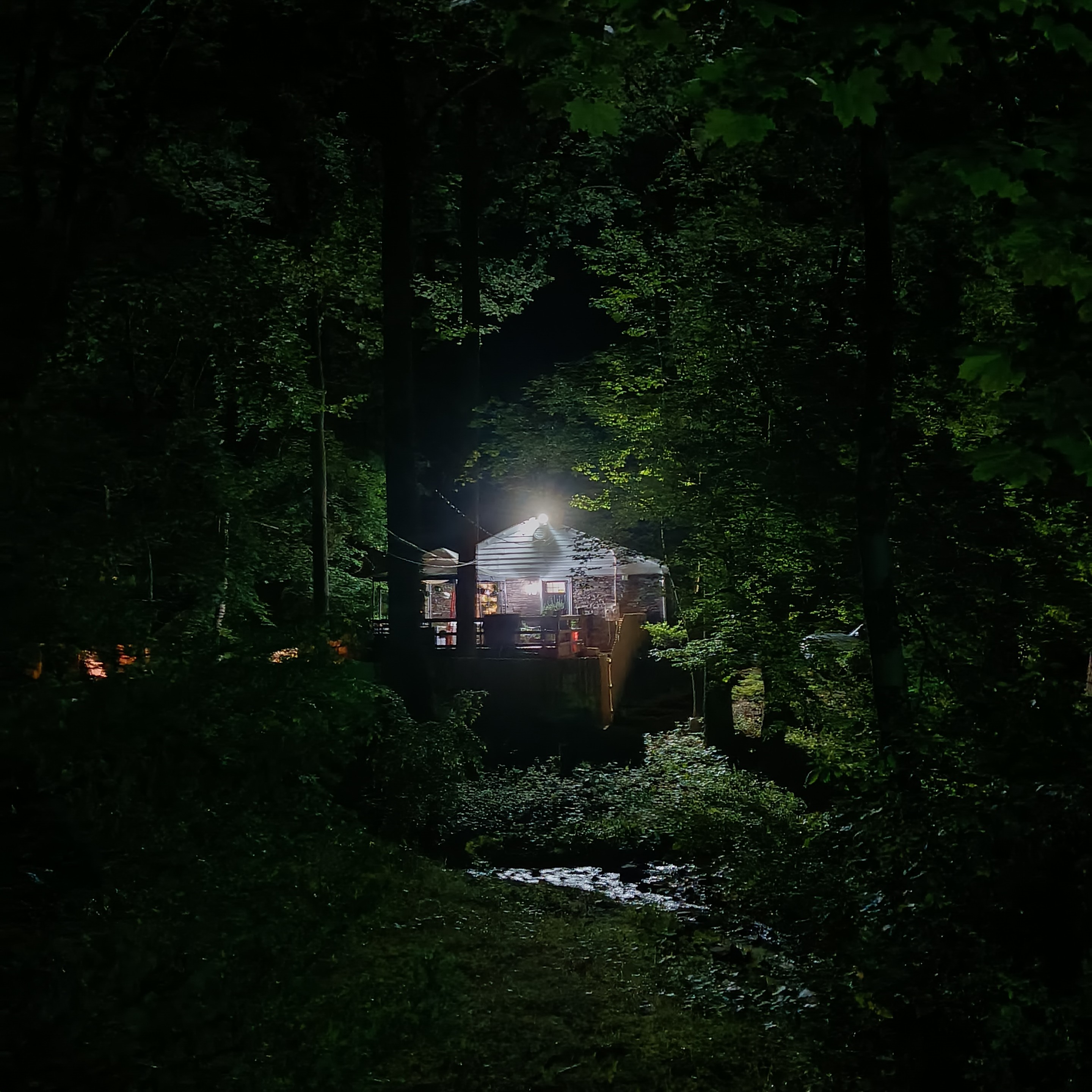 a good house at night nestled in the woods beside a creek