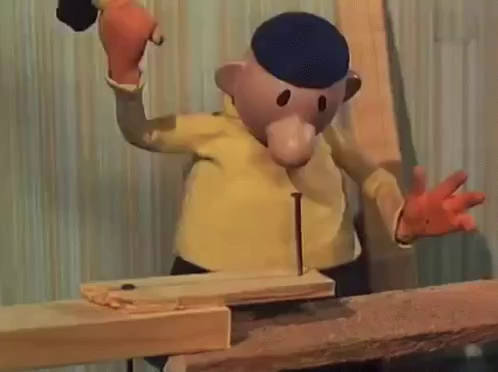 A claymation character with a yellow shirt and blue cap hammers a nail into wood. Animated scene conveys focus and determination.