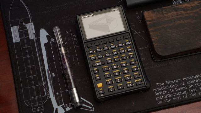 The SwissMicro DM42n sitting on a Space Shuttle mouse mat beside a fountain pen.