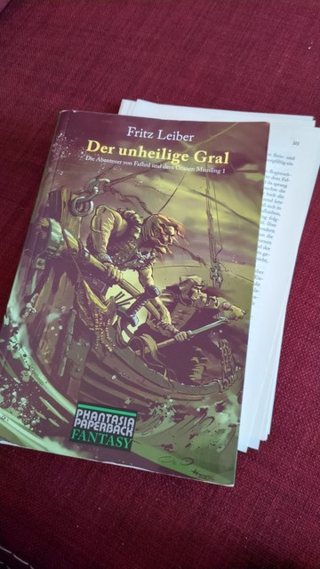 Cover des Buches "Der unheilige Gral - Die Abenteuer von Fafhrd und dem Grauen Mausling" von Fritz Leiber 

Darauf die beiden Protagonisten auf einem kleinen Boot auf sturmgepeitschter See.

Eingeklemmt in das Buch sind ein paar herausgefallene Seiten