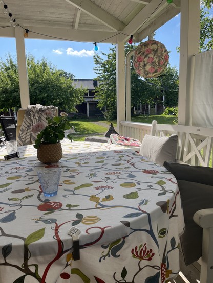 En sommarbild från en veranda med utsikt över gräsmatta, lada och äppelträd
