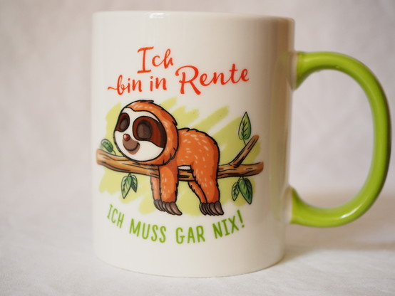 Eine Tasse mit einem aufgedrucktem Faultier. Die Aufschrift lautet: Ich bin in Rente. ICH MUSS GAR NIX!