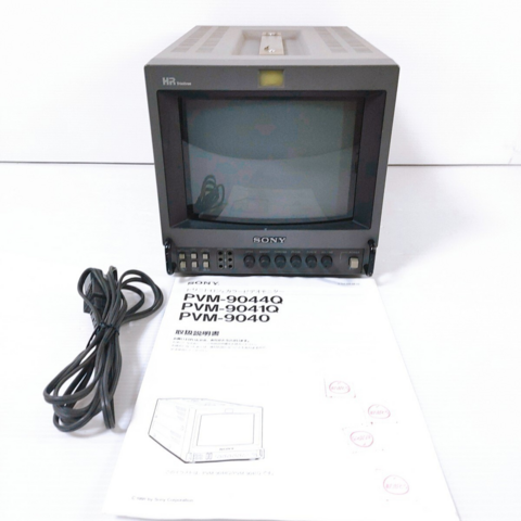 A picture of a Sony PVM-9044Q, a power cable, and an instruction manual.