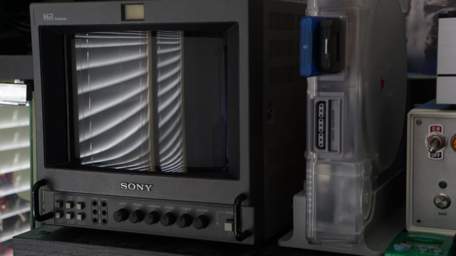 A picture of a Sony PVM-9044Q (known as the 8044Q in the US) sitting on top of a shelf beside a Sony SCPH-1001 PlayStation console in an acrylic shell.