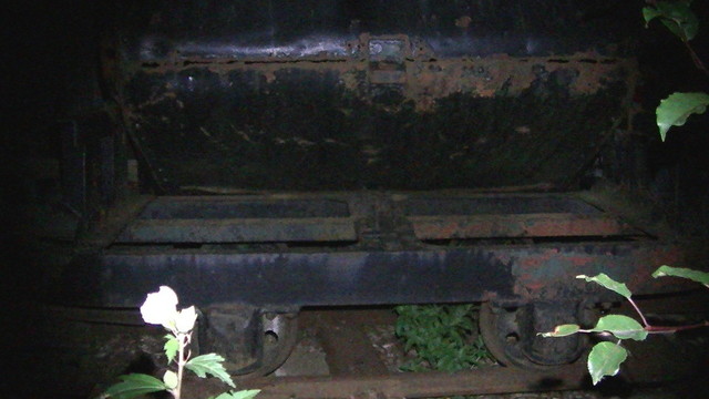 a black side tipping railway truck at night.