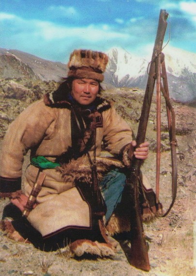 hunter with furs and coat and rifle, mountain in distance