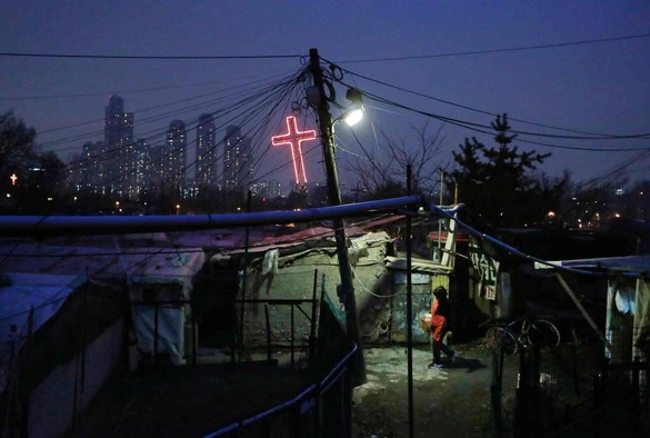 grimy shanty slum with an affluent city and its massive cross in the distance