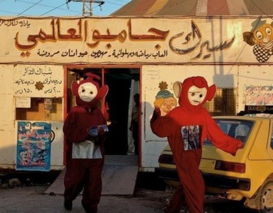people dressed up as teletubbies in front of store with arabic sign