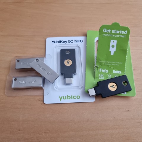 Three intenso usb thumb drives, and two YoubiKeys 5C NFC, on a table. One yubikey is still in it's package, the other one opened up. As are the three thumb drives.