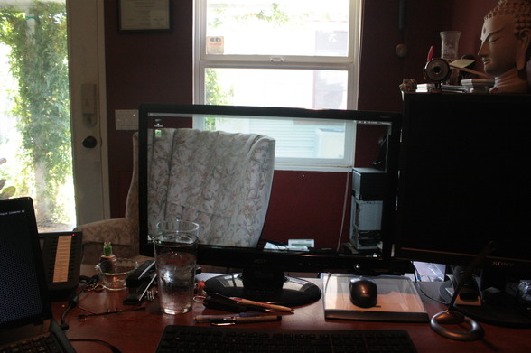View of computer on desk from the viewpoint of the user. You can only see the frame of the computer monitor. Magic!