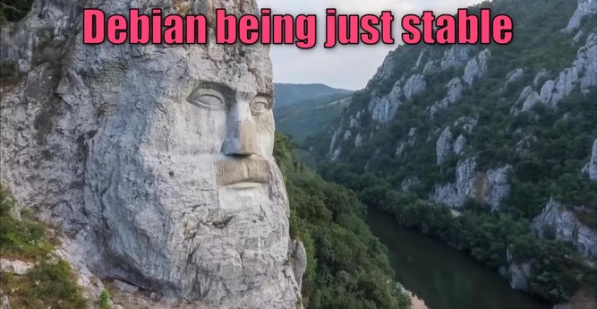 Stone face sculpture carved into a mountainside, overlooking a river valley. Text at the top reads "Debian being just stable" in pink font. The scene conveys grandeur and stability.