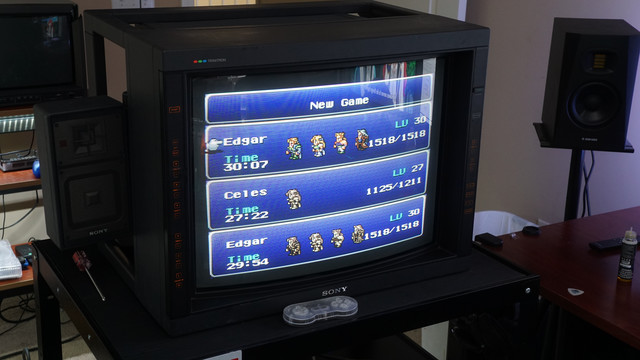 Sony PVM-2530 monitor on an AV cart showing the Final Fantasy 6 save game loading screen.  A clear acrylic SNES controller sits in front of the TV.