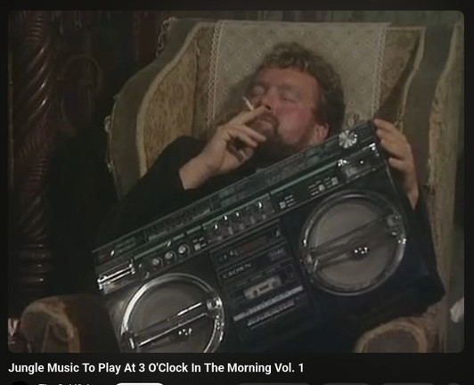 the jungle music priest chilling in father jack hackets chair, cigarette in mouth, holding a large boombox playing loud jungle music