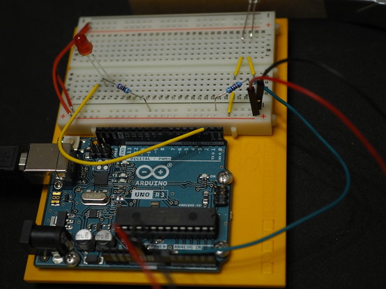 Ein Arduino Microcontroller mit einem kleinen Steckbrett, der Arduino und die Bauteile auf dem Steckbrett sind durch bunte Kabeln verbunden. 
