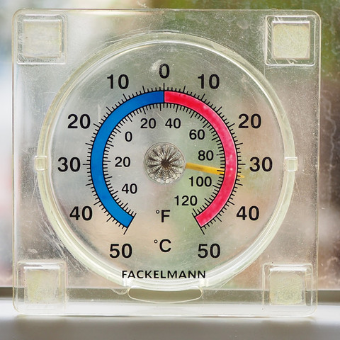Ein Thermometer, den man von außen an eine Glasscheibe kleben kann. Die Skala ist kreisförmig und in Celsius und Farenheit, der Zeiger ist gelb und steht auf über 30 Grad. 