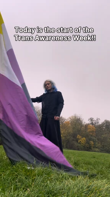 A non-binary person waves the non-binary flag while music plays. Text on screen shares messages about Trans Awareness Week.