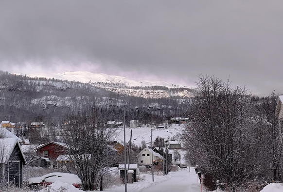 Photo of a snowy village, with a bright white mountain top in the distance