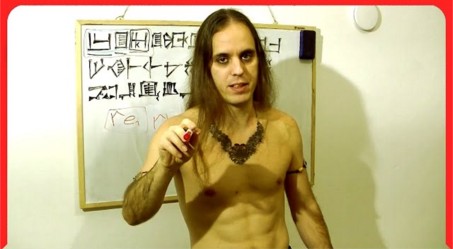 A shirtless Hungarian death metal linguist with cuneiform on a whiteboard behind him