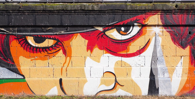 Eine Wandmalerei, welche den Hauptdarsteller von "Uhrwerk Orange" darstellt. Es ist nur ein Auschnitt eines Portraits. Oben Hutkrempe, dann Augen, schon die Nase ist abgeschnitten.