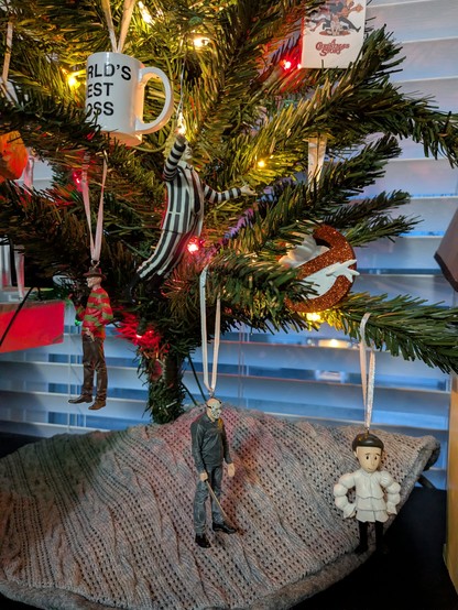 Freddy, Jason, and Beetlejuice Christmas ornaments hang next to a Jerry Seinfeld ornament.