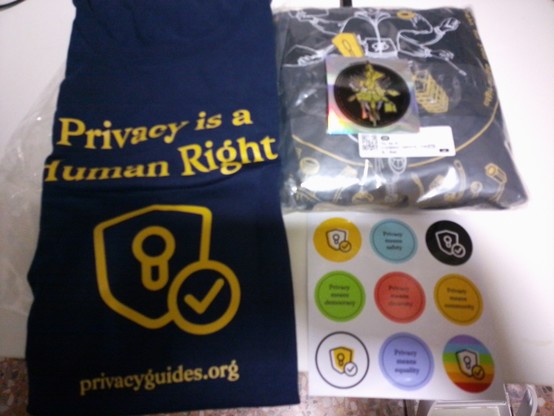 Se ven camisetas y pegatinas de privacyguides.org con lemas como "La privacidad es un derecho humano"