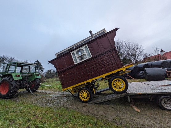 A showman's wagon on a trailer ramp with a tractor behind