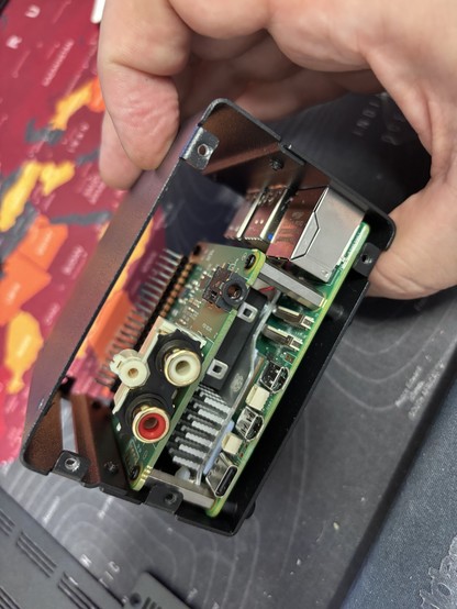 DAC+ installed on a raspberry pi 5 in a black metal case from the side. RCA and minijack connectors are visible. 