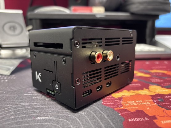 External view of tall, black, metal raspberry pi case with RCA and minijack connectors. A small power button is on the side next to a K logo. 