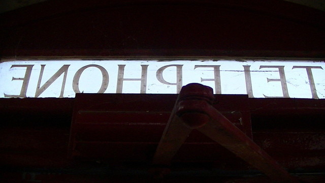 the illuminate "Telephone" sign on top of a british phone box, on the door, from inside. door damper also in view