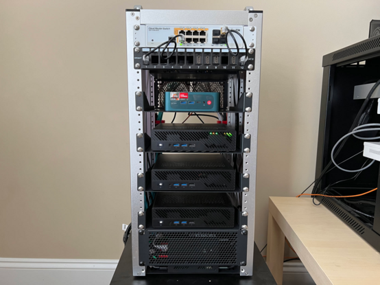 The front of the minirack showing a network switch, one Beelink Proxmox node, and three Minisforums MS-02 Proxmox nodes mounted in a minirack.