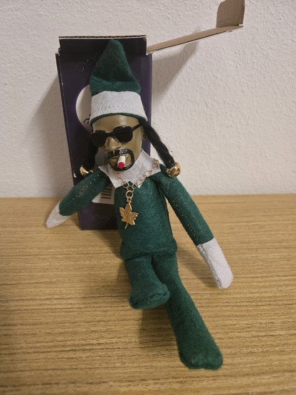 Snoop dog doll as "elf on the shelf" with joint in his mouth, and necklace with weed pendant.
He's also have 2 dreads with jingle bells on it and sunglasses. 