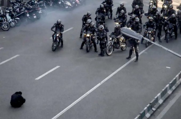 Iranian protestor in front of a bunch of motorcycle cops
