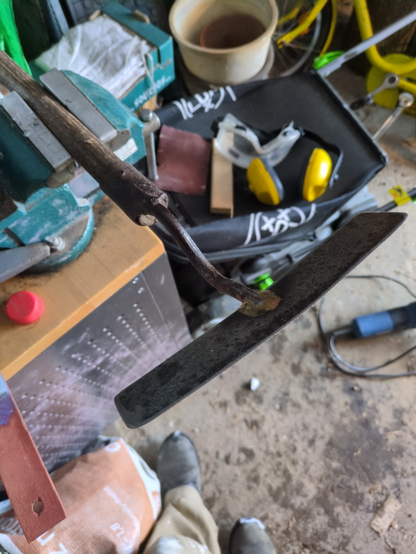 Eine Schuffel. Quasi ein schmales Metallblatt mit geschärften Kanten an einem Metallsteg und einem langen Stiel