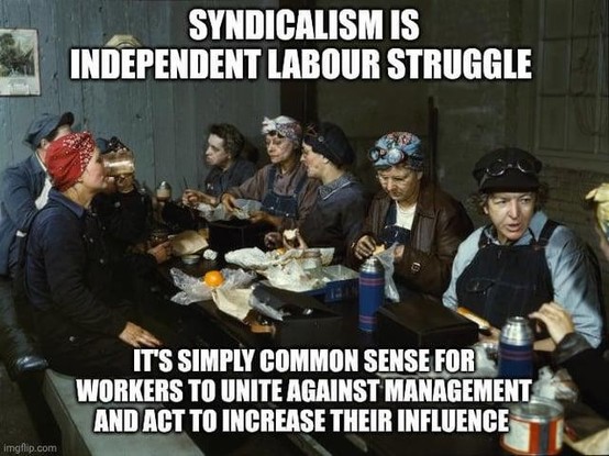 A meme showing a group of factory workers, mostly women, seated closely around a long table during a meal break, wearing work clothes, headscarves, and protective goggles in an industrial setting. Overlaid text at the top reads “SYNDICALISM IS INDEPENDENT LABOUR STRUGGLE,” and text at the bottom reads “IT’S SIMPLY COMMON SENSE FOR WORKERS TO UNITE AGAINST MANAGEMENT AND ACT TO INCREASE THEIR INFLUENCE.”