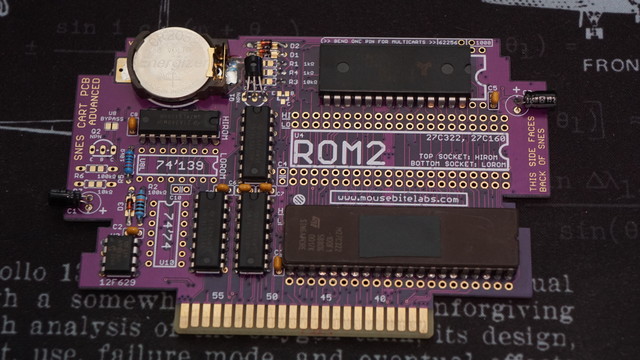 A picture of MouseBiteLabs SNES CART PCB populated with all the things needed for a real SNES cartridge.  The ST 27C322 EPROM is in the lower-right hand corner of the PCB.