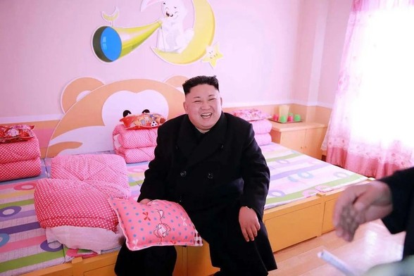 Smiling jolly North Korean leader Kim Jong-un at the boarding school for orphans in Pyongyang. Pretty pink beds.
Photo: KCNA VIA KNS / AFP PHOTO 