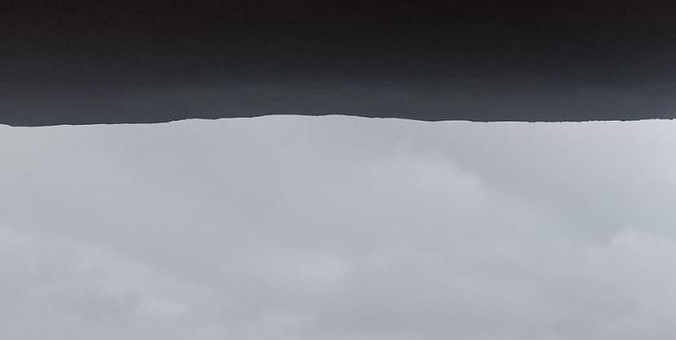 Vista do céu de uma janela de apartamento, com nuvens escuras muito carregadas.