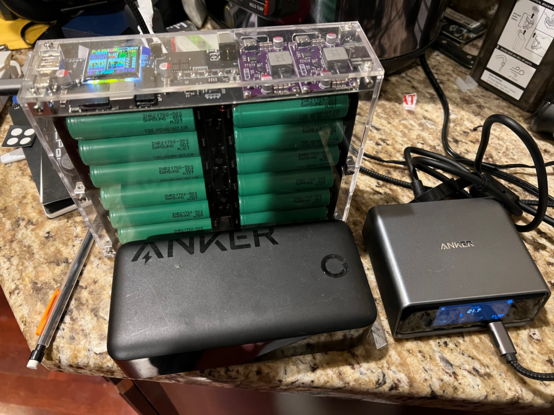 An AliExpress massive battery bank being charged via the Anker charger sitting behind another Anker battery bank.
