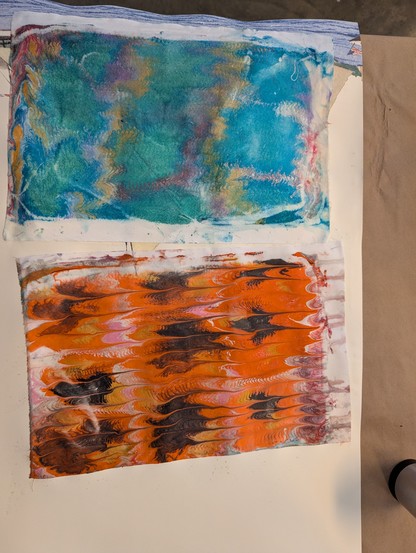 Two boys of fabric that were hand marbled. One in orange and black and one with green and teal as primary colors