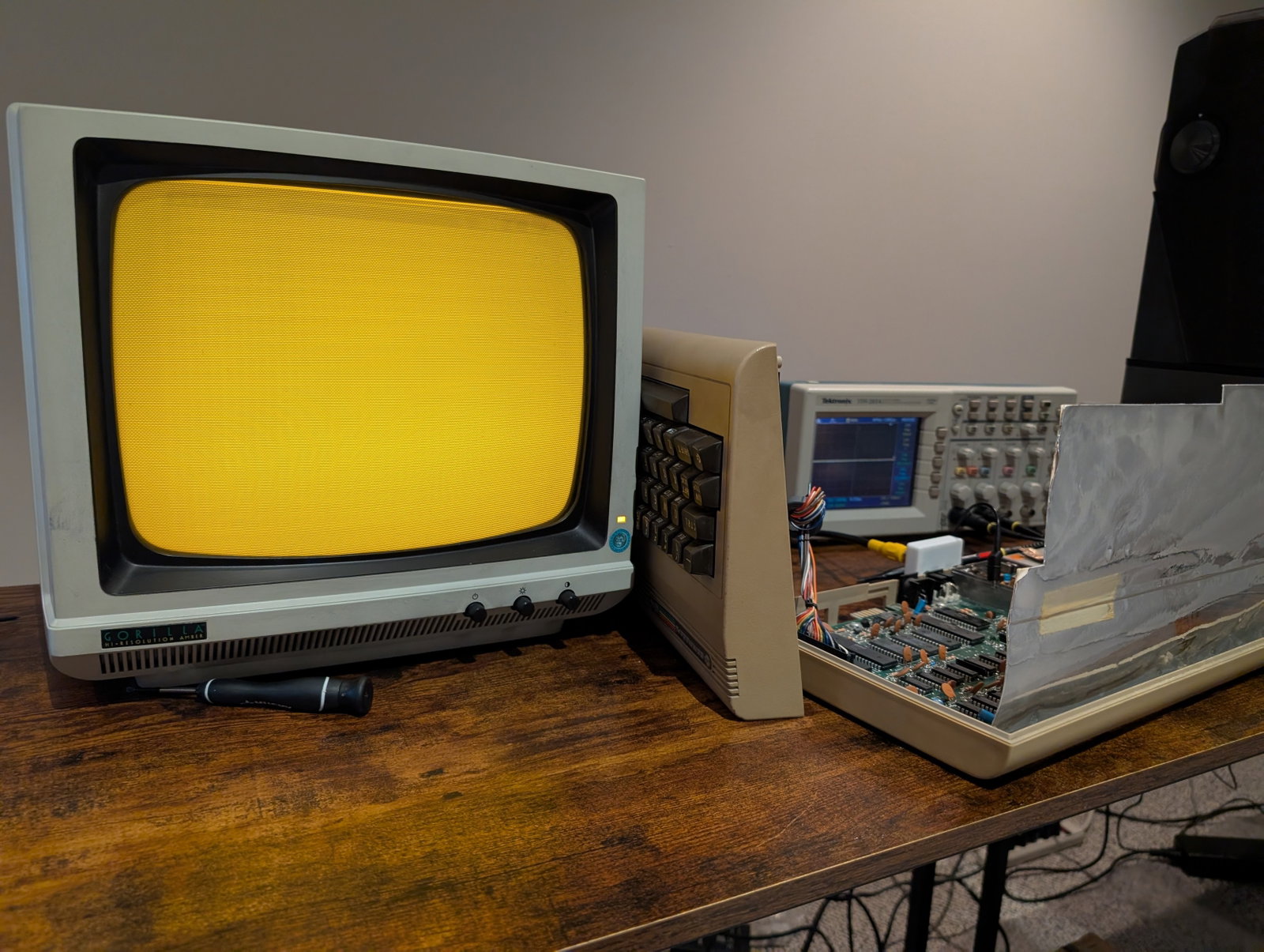 A Commodore 64 next to a CRT monitor, with an oscilloscope in the back.