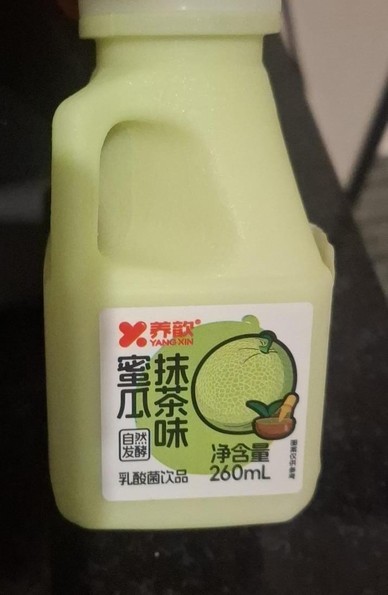 Uma estranha bebida esverdeada dentro de um pote plástico. O rótulo contém caracteres em chinês e o desenho de um melão.