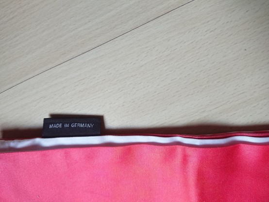 Embroidered label out of shiny yarn, saying "MADE IN GERMANY".