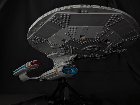 A view of the Lego model of the NCC-1701-D. Shot from the classic lower front quarter dorsal view of the saucer and secondary hull, it's slightly lit in front of a black cloth background.

She's beautiful....