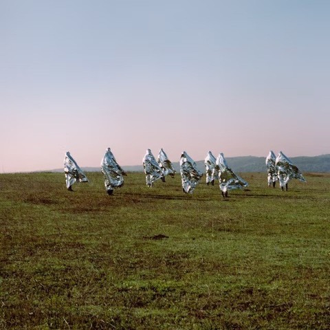 group of women in silver white burkas walking through field