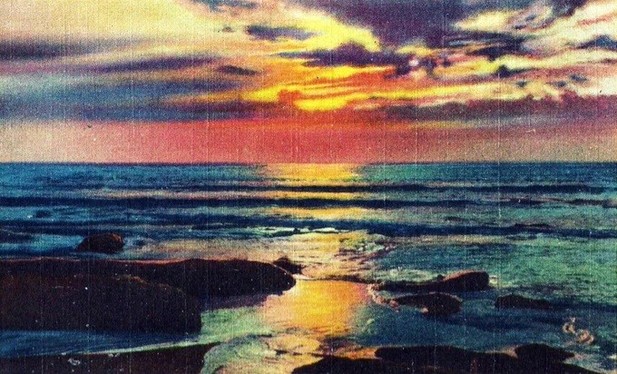 colorful red and yellow and orange sunset mixing with grayish purplish clouds and blue and teal sea