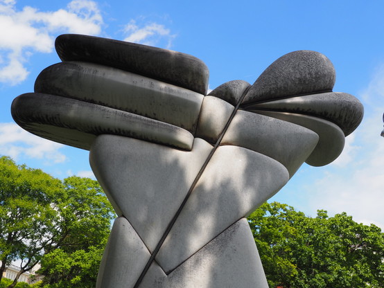 Eine Steinskulptur. Zitat von austriasites.com: "der abstrakte Körper aus Stein, der aus Bindungen quillt" 