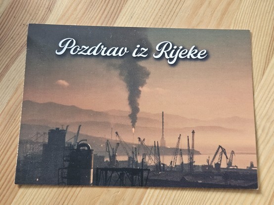 Razglednica sa fotografijom koja prikazuje smog i dimnjak rafinerije iz kojeg suklja gusti tamni dim