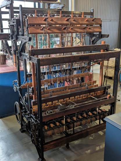 A structure of iron and wood has cotton thread laced through it and looks like a sophisticated, but relatively simple, mechanism.

Science Museum Group. Object no. Y6000.423