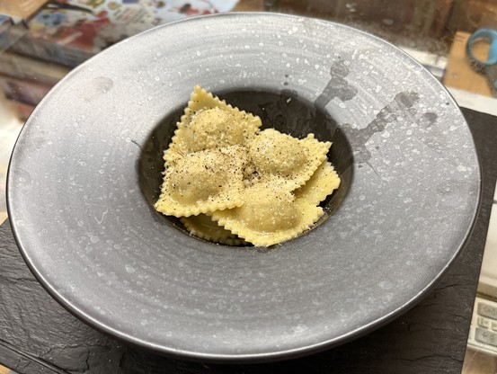 Eight home-made ricotta & nuts ravioli in one of those fancy plates that look like a little bowl surrounded by an actual plate